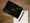 Tablet showing green stock chart with pen and paper on desk.