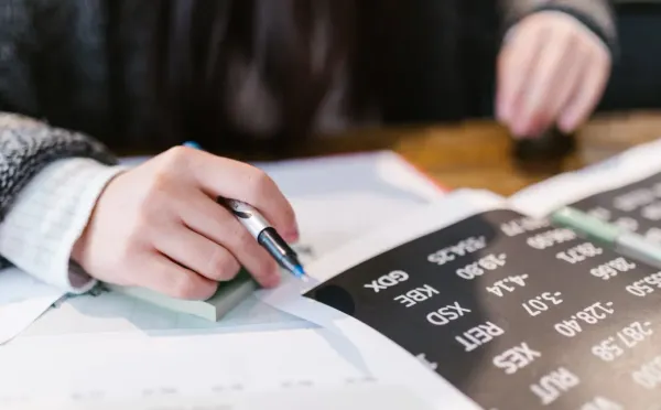 Person reviewing forex data and writing notes.