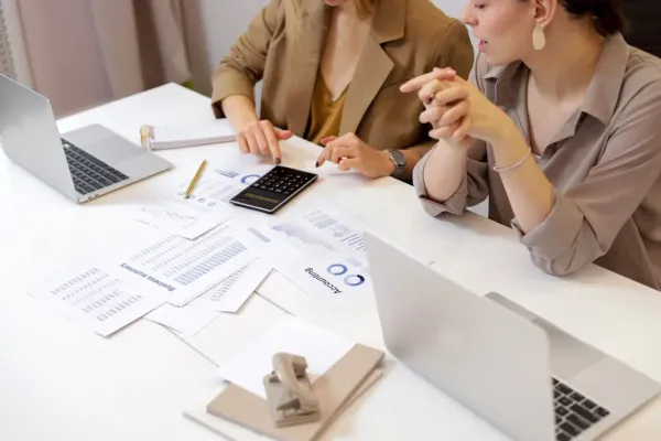 Two businesswomen collaborate on financial reports.