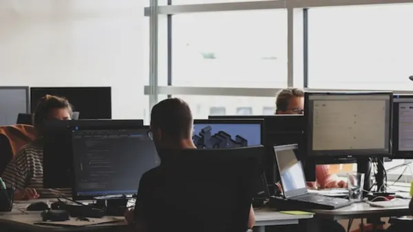 Team in office, working on laptops and computer.